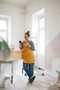 Happy young woman having break during renovation her aparatment. Using phone, searching inspiration at social medias. Royalty Free Stock Photo