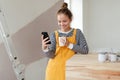 Happy young woman having break during renovation her aparatment. Using phone, searching inspiration at social medias. Royalty Free Stock Photo