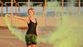 Happy young woman having fun with colorful powder cloud. girl running with yellow color smoke bomb Royalty Free Stock Photo