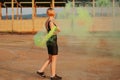 Happy young woman having fun with colorful powder cloud. girl running with yellow color smoke bomb Royalty Free Stock Photo