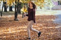 Happy young woman having fun time in autumn outdoors. Cheerful smiling girl jumping running in the fall forest. Royalty Free Stock Photo