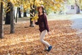 Happy young woman having fun time in autumn outdoors. Cheerful smiling girl jumping running in the fall forest. Royalty Free Stock Photo