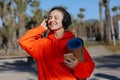 Happy young woman In headphones with yoga mat, listens music on smartphone outdoors. Smiling girl with closed eyes in Royalty Free Stock Photo