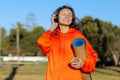 Happy young woman In headphones with yoga mat, listens music on smartphone outdoors. Smiling girl with closed eyes in Royalty Free Stock Photo