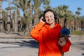 Happy young woman In headphones with yoga mat, listens music on smartphone outdoors. Smiling girl with closed eyes in Royalty Free Stock Photo