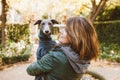 Happy young woman with her Italian Greyhound dog. Home pets. Young woman is holding and hugging her cute curious levrette puppy