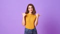 Happy young woman her pointing hand over purple banner background with copy space Royalty Free Stock Photo