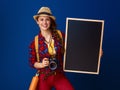 Happy young woman hiker with digital camera showing blackboard