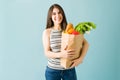 Happy young woman is holding a bag of groceries with vegetables Royalty Free Stock Photo