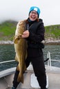 Happy young woman holding big arctic cod. Norway happy fishing. Fisherwoman with cod fish in hands Royalty Free Stock Photo