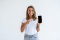 Happy beautiful young woman holding blank screen mobile phone and pointing finger over white background Royalty Free Stock Photo