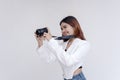 A happy young woman holding a camera in eye-level while taking pictures. Isolated on a white background Royalty Free Stock Photo