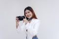 A happy young woman holding a camera in eye-level while taking pictures. Isolated on a white background Royalty Free Stock Photo