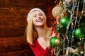 Happy young woman holding Christmas bauble in front of Christmas tree. Beauty girl decorating Christmas tree. Girl is Royalty Free Stock Photo