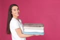 Happy young woman holding clean towels on color background. Laundry day Royalty Free Stock Photo