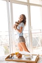 Happy young woman holding dog standing at the window Royalty Free Stock Photo