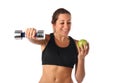 Happy young woman holding a dumbbell and a green apple