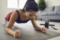 Happy smiling young woman holding a plank position during a fitness workout at home