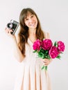 Happy young woman holding in hands bouquet of peonies and old vintage camera. Sweet romantic moment. Smiling woman Royalty Free Stock Photo