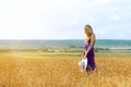 Happy young woman holding hat, walking in the golden wheat field. Sunset light. Summer nature. Royalty Free Stock Photo