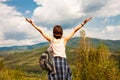 Happy young woman holding her hands up and enjoying beautiful mountain landscape. Back view. Freedom concept. Vacation in the Royalty Free Stock Photo
