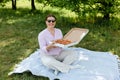 Happy young woman holding hot pizza in box on nature background. Attractive girl feels hungry and loves the taste