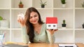Happy young woman holding house models and smiling at camera. Real estate, mortgage loan and home insurance concept Royalty Free Stock Photo