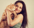 Happy young woman holding and hugging with love on the hands her red maine coon kitten and kissing. Closeup Royalty Free Stock Photo