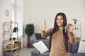 Happy young woman holding keys to her new apartment, smiling and giving thumbs-up