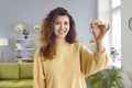 Happy young woman holding keys to her new apartment