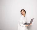 Happy young woman holding laptop computer by white wall Royalty Free Stock Photo