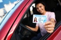 Happy young woman holding license while sitting in car, focus on hand. Driving school Royalty Free Stock Photo