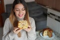 Happy young woman holding and looking a slice of Panettone traditional Christamas cake with raisins and candied fruits indoor
