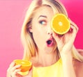 Happy young woman holding oranges halves