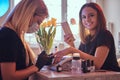 Happy young woman holding a phone an looking at a camera in a beauty salon while manicure master doing beauty procedure Royalty Free Stock Photo