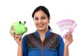 Happy young woman holding a piggy bank and Indian rupee notes Royalty Free Stock Photo