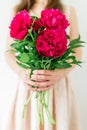 Happy young woman holding red peony bouquet in hands. Sweet romantic moment Royalty Free Stock Photo