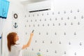 Happy Young Woman Holding Remote Control Relaxing Under The Air Conditioner. Royalty Free Stock Photo