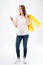 Happy young woman holding shopping bags and mobile phone Royalty Free Stock Photo