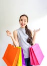 Happy young woman holding shopping bags and mobile phone. Makes online shopping on a tablet. Beautiful asian girl carrying Royalty Free Stock Photo