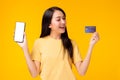 Happy young woman holding smart phone and credit card and look at credit card with satisfied smile face. Use for your advertising Royalty Free Stock Photo