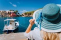 Happy young woman holding straw hat enjoying vacations in Assos village in front of emerald bay of Mediterranean sea