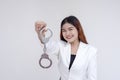 A happy young woman holding up a free handcuff in front of the camera. Isolated on a white background