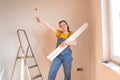 Happy young woman holding wallpaper rolls with roller. DIY home apartment renovations.