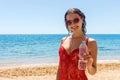 Happy young woman holding a water on the beach. Portrait of a happy girl holding a water bottle outdoors on the beach