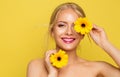 Happy Young Woman holding Yellow Flower in front of Eye. Cheerful Beauty Model Face over Orange background. Women Natural Facial Royalty Free Stock Photo