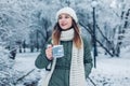 Happy young woman holds cup dressed in knitted Christmas case in winter park with vacuum flask. Hot drink Royalty Free Stock Photo