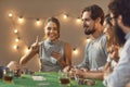 Happy young woman holds up finger as she has lucky hand in poker game with friends