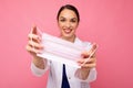 Happy young woman holds and wears a white medical mask to protect yourself from corona virus, cares for her health and