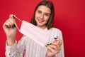 Happy young woman holds and wears a white medical mask to protect yourself from corona virus, cares for her health and